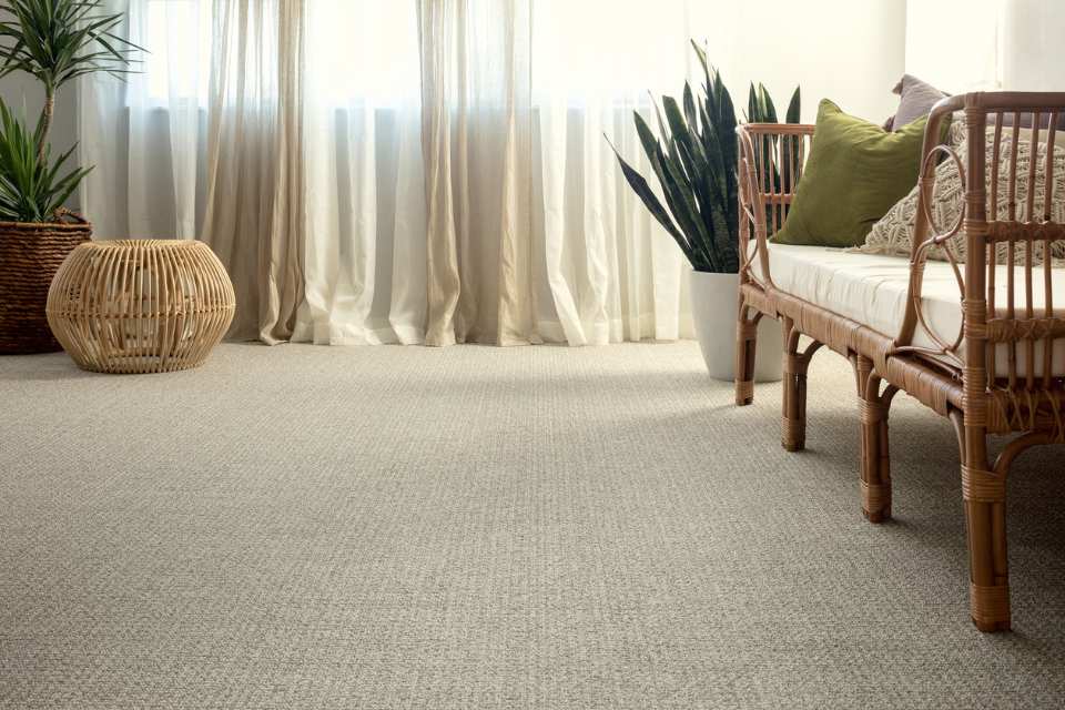 beige textured carpet in sitting area with rattan bench and pops of green